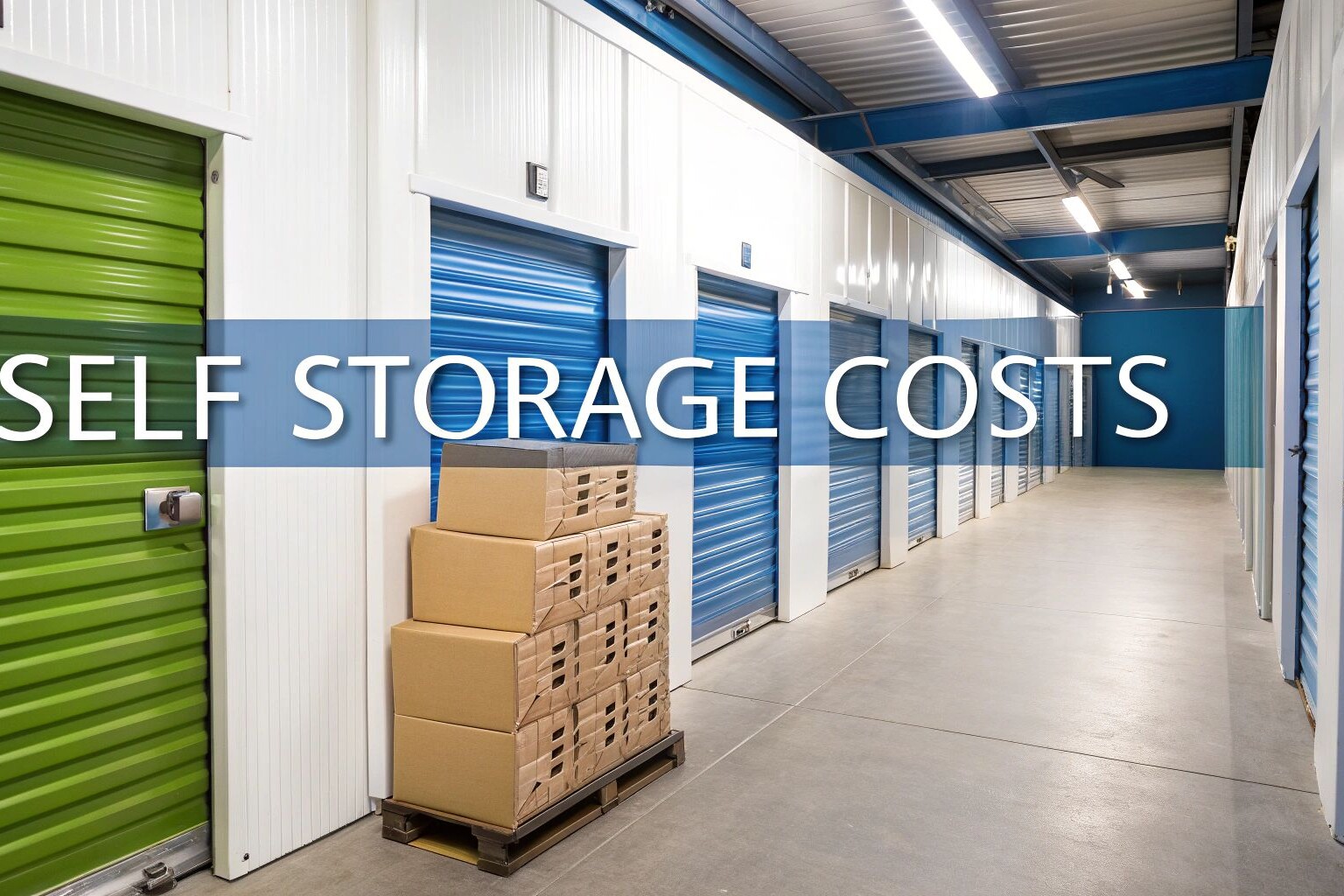 A hallway with blue and green storage unit doors, a stack of cardboard boxes on a pallet, and the words 